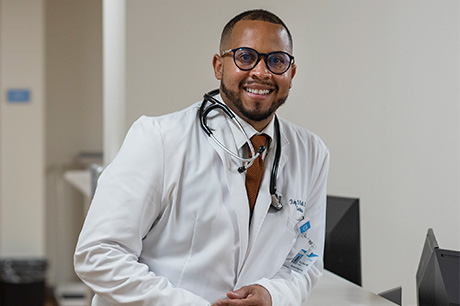 Healthcare provider standing at a nurses' station in a clinical setting.
