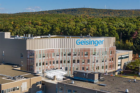 Aerial view of a Geisinger healthcare facility surrounded by parking areas and wooded hillsides.