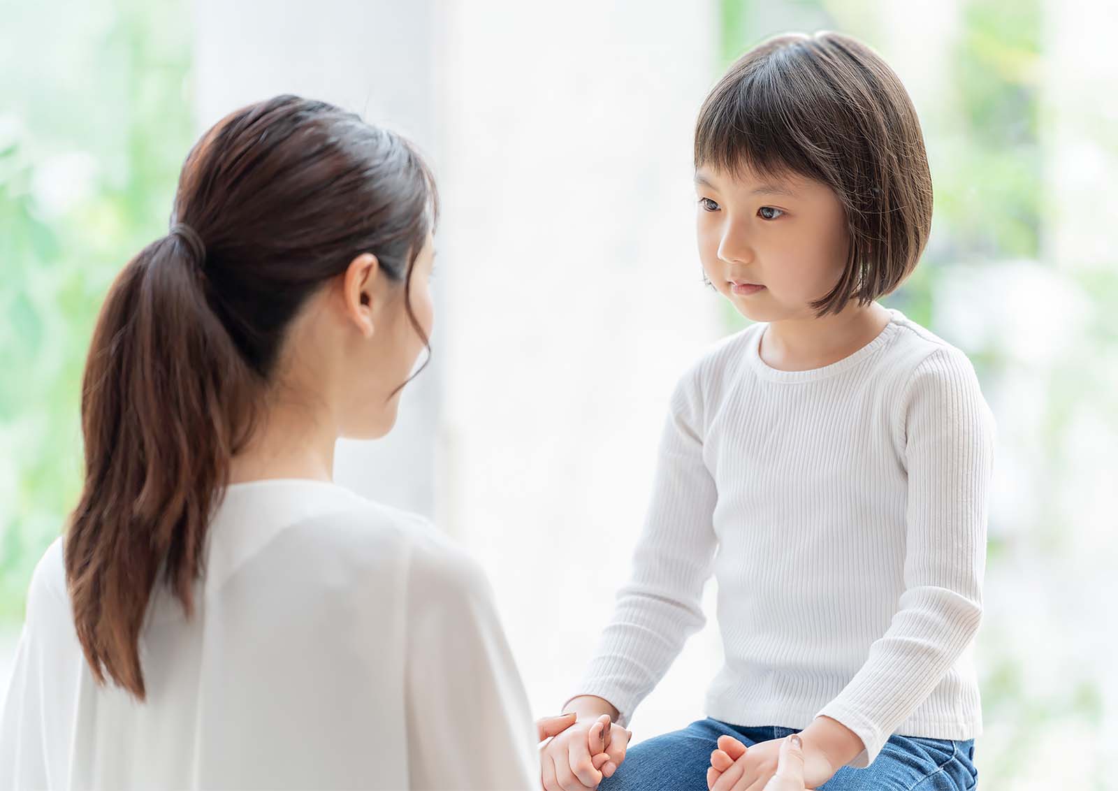 Adult and child sitting together and holding hands during a supportive conversation.
