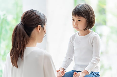Adult and child sitting together and holding hands during a supportive conversation.