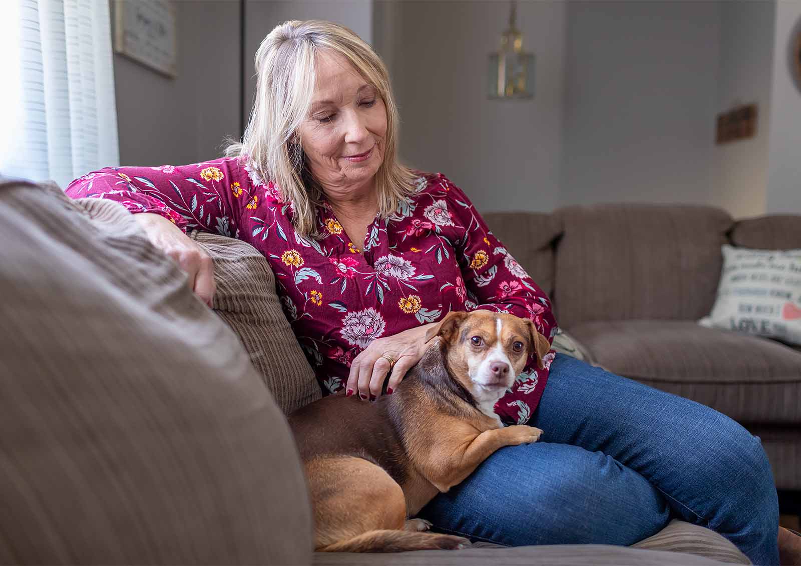 Ellen Fogleman sits on the couch and enjoys a moment with her dog.