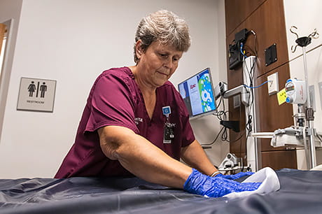 A hospital EVS technician sanitizers a gurney in preparation for patient use.