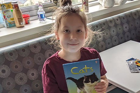 A young female patient shows the book she's reading about cats.