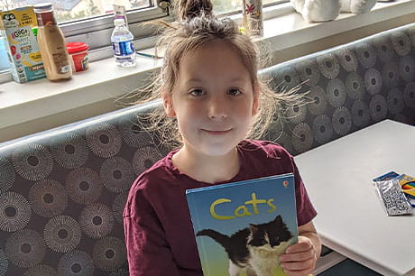 A young female patient shows the book she's reading about cats.