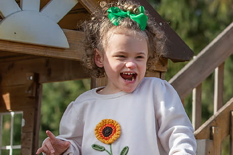 A young Miracle Kid plays on a swing set.