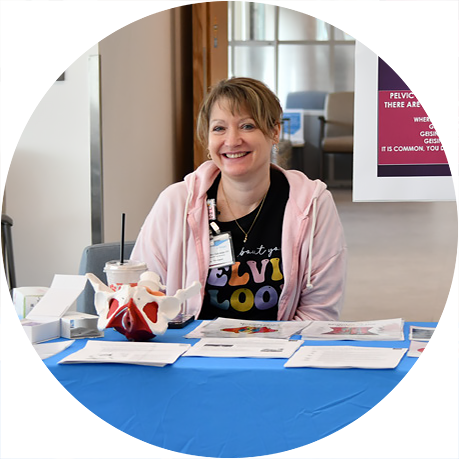 Community health event table with staff member providing wellness information and resources to support healthy living initiatives.