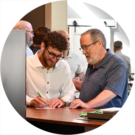 Two professionals collaborating at a desk, reviewing documents and writing notes during a business or leadership meeting.