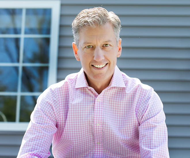 Portrait of a professional outdoors in front of a home, representing community leadership and healthcare advocacy.