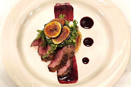 A prepared plate of venison with Bordelaise sauce.