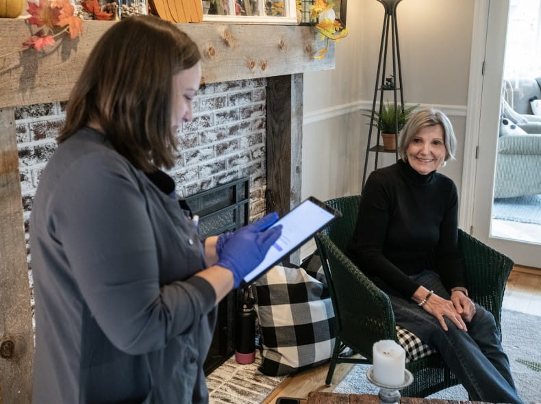a woman sitting in a chair at home talking to a nurse
