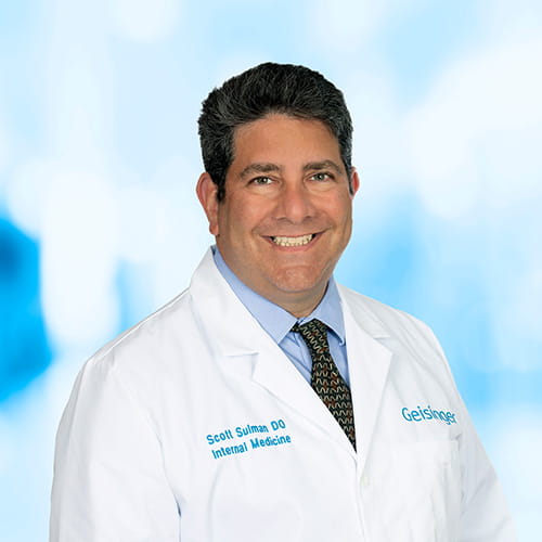 Headshot of Dr Sulman on white and blue background