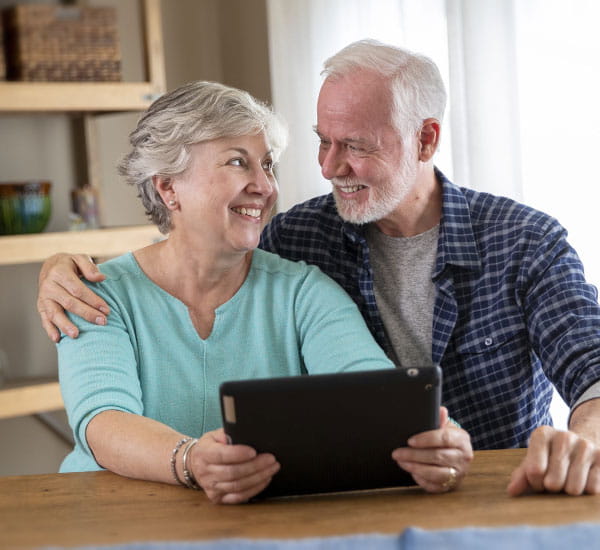 Senior Couple holding a tablet smiling from the ease of paying their bill online at Geisinger.