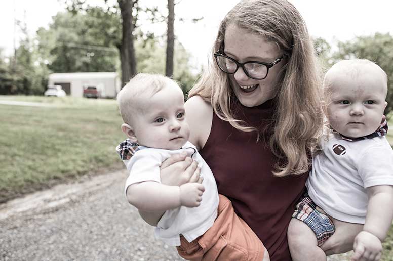 Adult female holding babies in each arm.